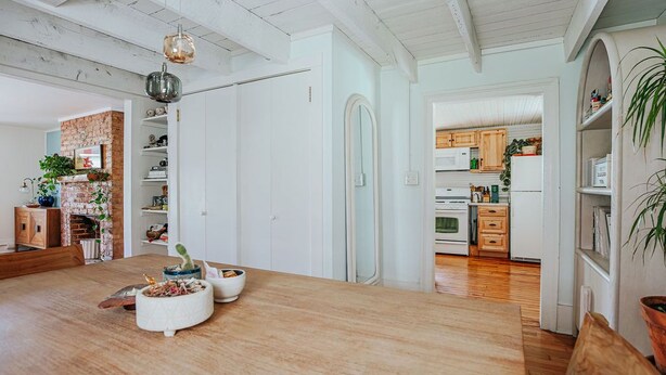 A spacious dining area with a wooden table, white walls, and a kitchen in the background. - The Mariposa (Staunton)
