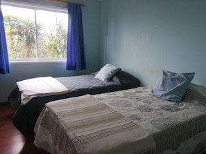A room with two beds, a window with curtains, and a view of greenery outside. - Oceana Suites Hacienda Limache (Limache)