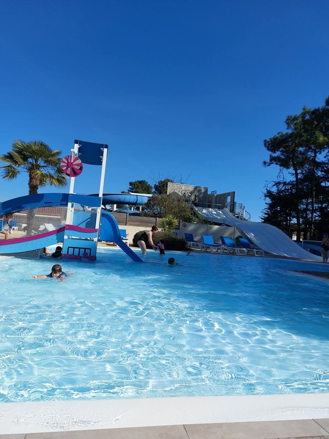 Ein Schwimmbecken mit Wasserrutsche und Rettungsschwimmturm.