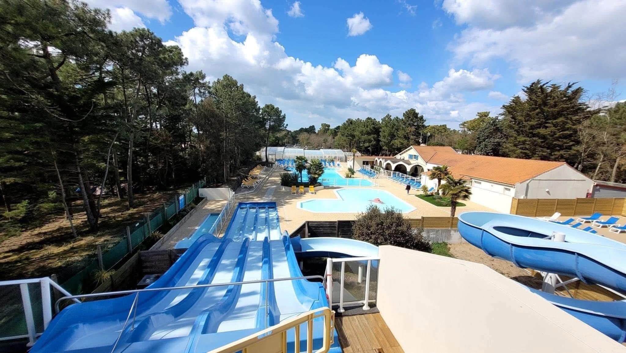 A water park with multiple slides, pools, and a building with a tiled roof.