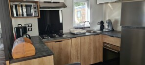Eine kleine Küche mit Gasherd, Spüle und modernen Geräten.