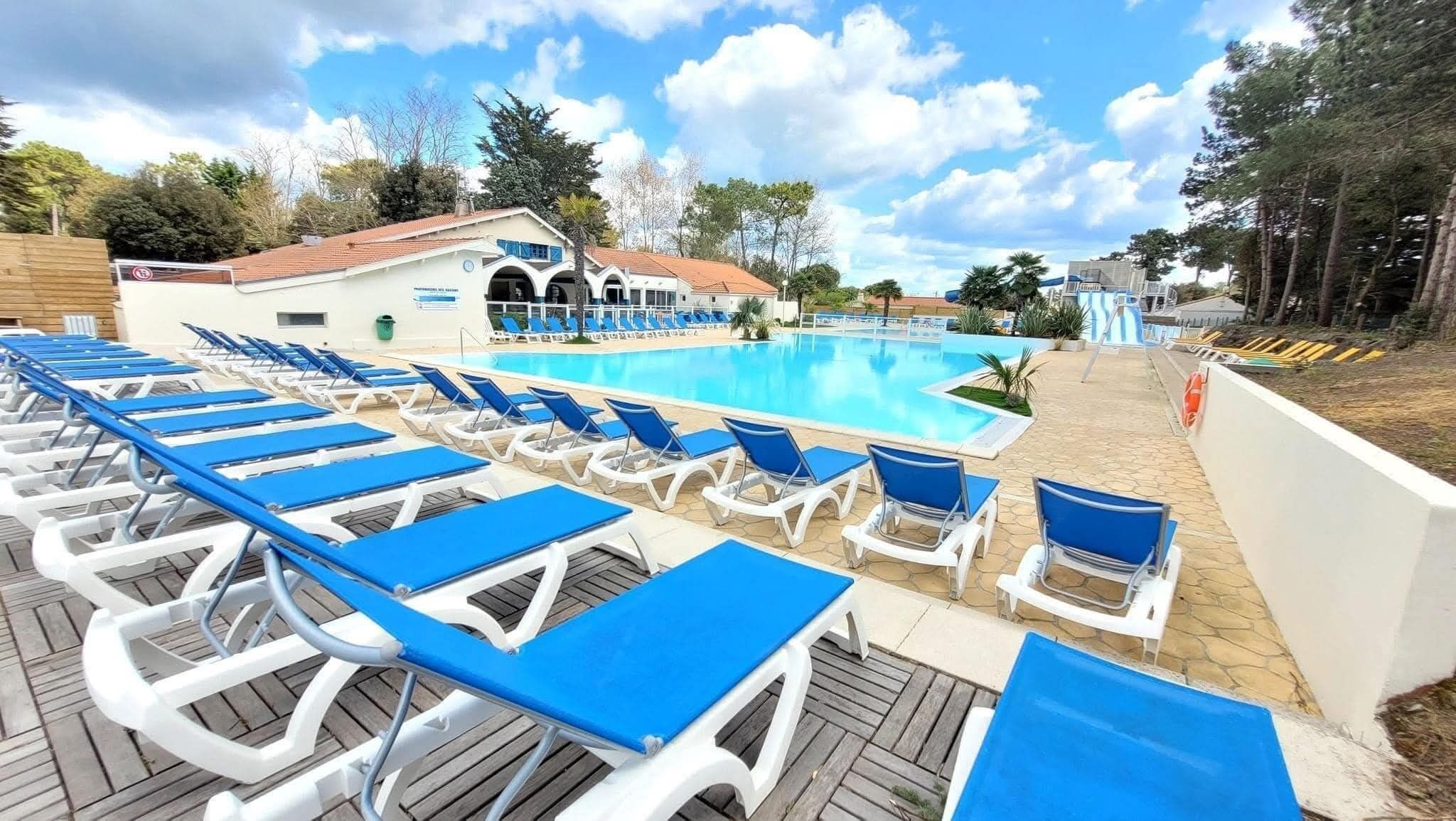 A poolside area with sun loungers and a building with a red roof.