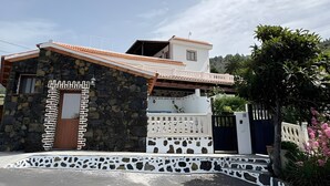 Ein zweistöckiges Haus mit einer Stein-Fassade, einem Ziegeldach und einem weißen Zaun mit verzierten Ausschnitten.