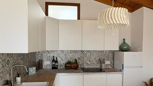 Eine moderne Küche mit Holzbalken, weißen Schränken, einer gefliesten Spritzschutzwand und einer hängenden Leuchte.