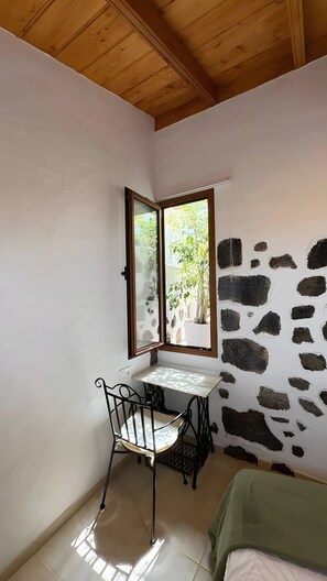 A room with a stone wall, a window, a table with a chair, and a bed. - Holiday Home 'Lagar De Elba' with Sea View, Private Pool and Wi-Fi (Las Manchas)