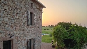 Un bâtiment en pierre avec une cour en gravier, des sièges en plein air et une vue sur la campagne.