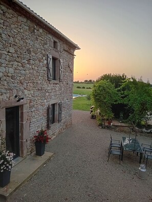 A stone building with a gravel courtyard, outdoor seating, and a view of the countryside. - Country house, ideally located in the Tarn! (Tonnac)