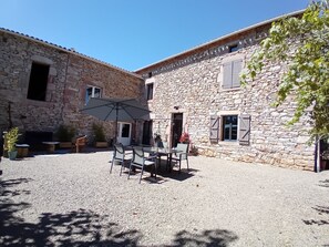 A stone building with a courtyard, outdoor seating, and a large umbrella. - Country house, ideally located in the Tarn! (Tonnac)