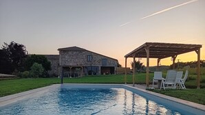 Une piscine avec une maison en pierre en arrière-plan.
