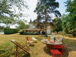 A patio with outdoor furniture, a round table, and a large tree. - Welcome to the Serrepile large holiday home,large swimming pool and tennis court (Lempaut)