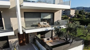 Una casa moderna de dos pisos con balcón, mobiliario exterior y un jardín.