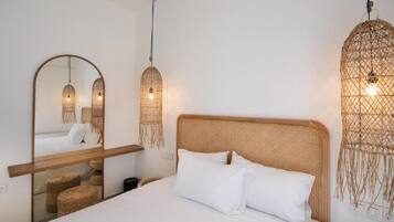 A bedroom with a large mirror, a bed with white bedding, and woven wall hangings.