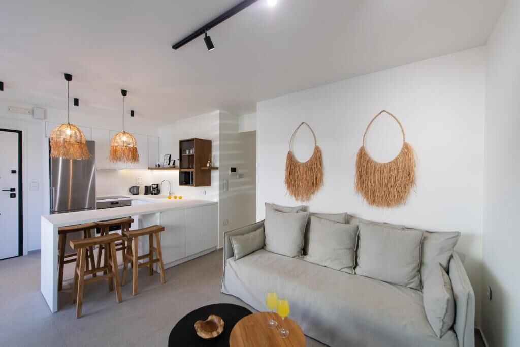 A modern kitchen with a central island, bar stools, and pendant lighting.