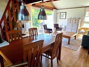 A dining area with wooden furniture, pendant lights, and a view of the outdoors.