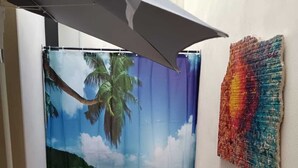 En lille patio med et bord og stole, et mural af en strandscene, og et farverigt kunstværk på væggen.