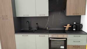 Et moderne køkken med lysegrå skabe, en sort bordplade, en vask, en kaffemaskine og en ovn.