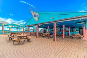 Ein Sonnendeck eines Kreuzfahrtschiffs mit Außenbereich, einer Bar und einem Rettungsboot.