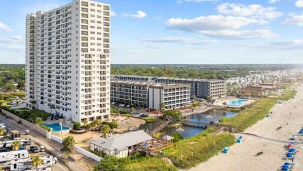 Um hotel moderno com vários andares, piscina e área de praia.