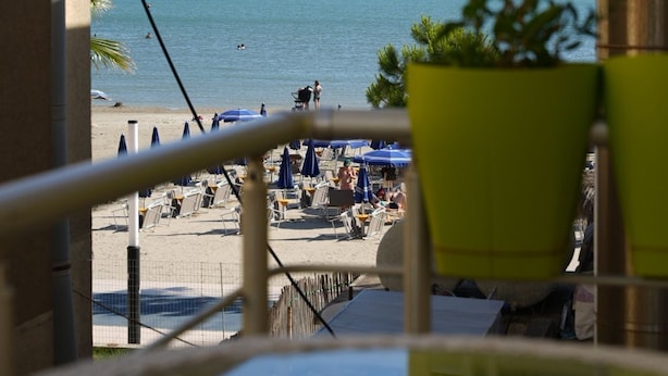 A balcony with a view of the beach, a table, chairs, and a potted plant. - Klegis Room (Durrës)