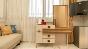 A modern room with a sofa, a wooden desk with drawers, a flat-screen TV, and a coffee maker. - Klegis Room (Durrës)