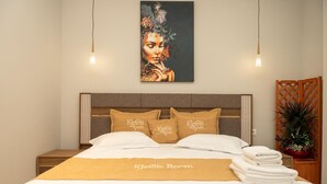 A hotel room with a bed, pillows, a blanket, a painting, and a plant. - Klegis Room (Durrës)