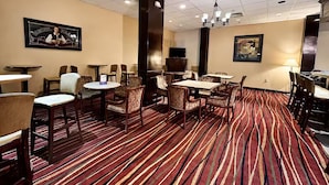 Un vestíbulo de hotel con varias zonas de estar, un televisor y una alfombra estampada.