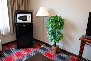 Una habitación pequeña con microondas, lámpara y planta en maceta.