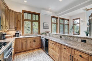 Eine Küche mit Holzausstattung, Arbeitsplatte aus Granit und Blick ins Freie.