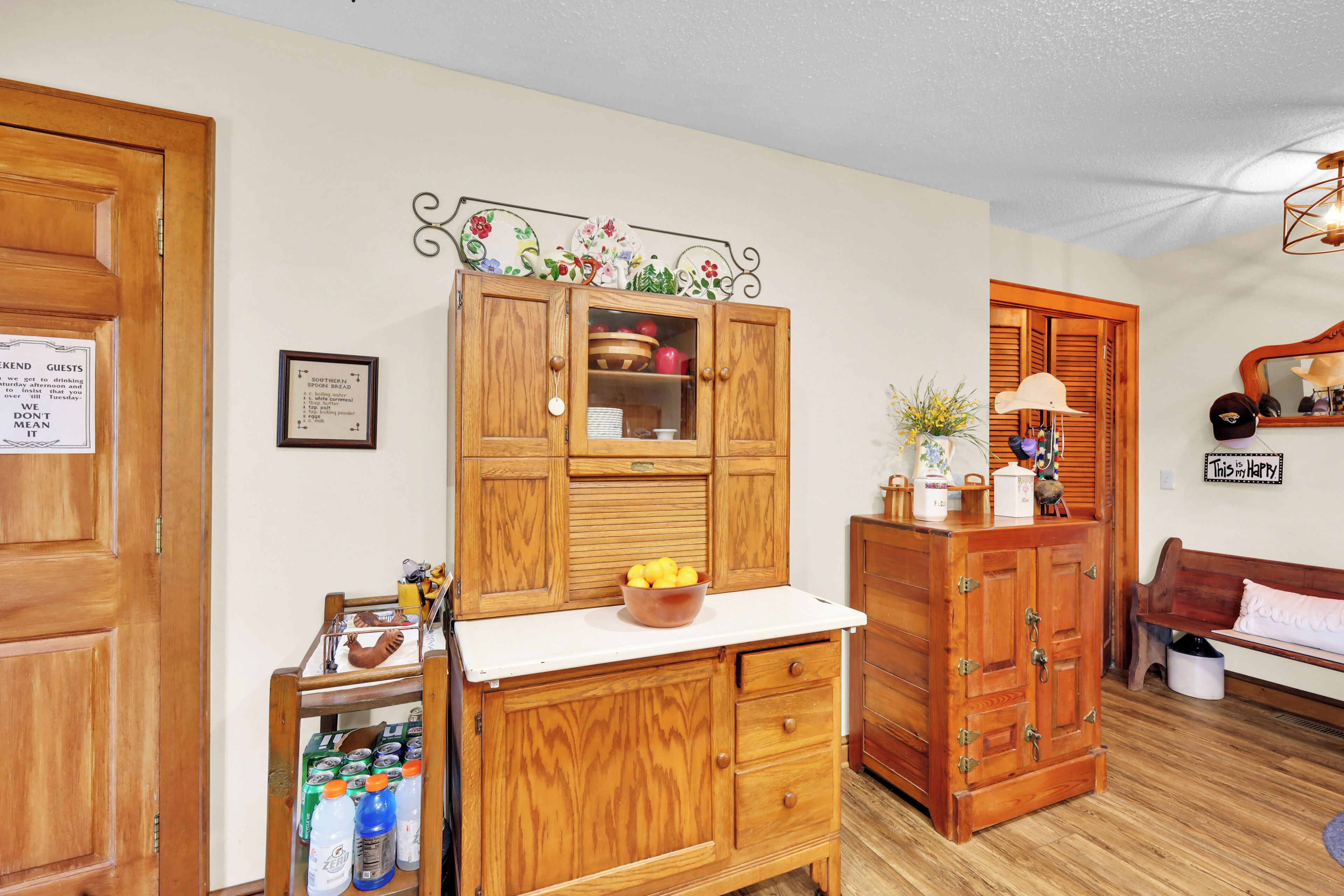 A wooden cabinet with a glass door, a bowl of lemons on top, and a sign on the wall.