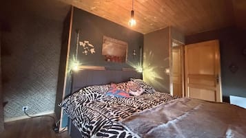 Ein Schlafzimmer mit einem Bett, Holzboden und einer Tür.