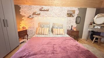 A bedroom with a bed, wooden headboard, a dresser, a mirror, and a wardrobe.