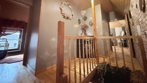 A wooden interior with a staircase, a wall with a wreath, and a window. - La clos de la ch'tite d'alsace (Crespin)