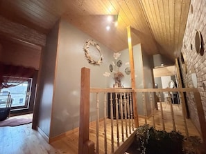 Un interior de madera con una escalera, un adornado en la pared y una ventana.