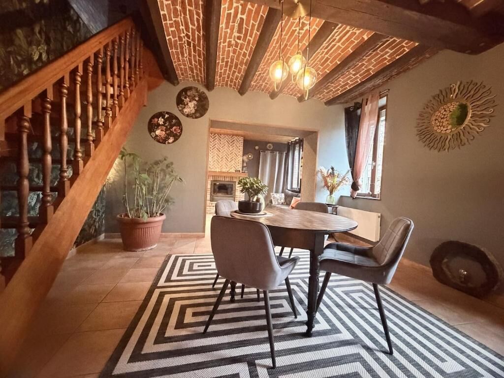 Un coin repas avec une table en bois, des chaises et un tapis à motifs.