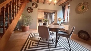 A dining area with a wooden table, chairs, and a patterned rug. - La clos de la ch'tite d'alsace (Crespin)