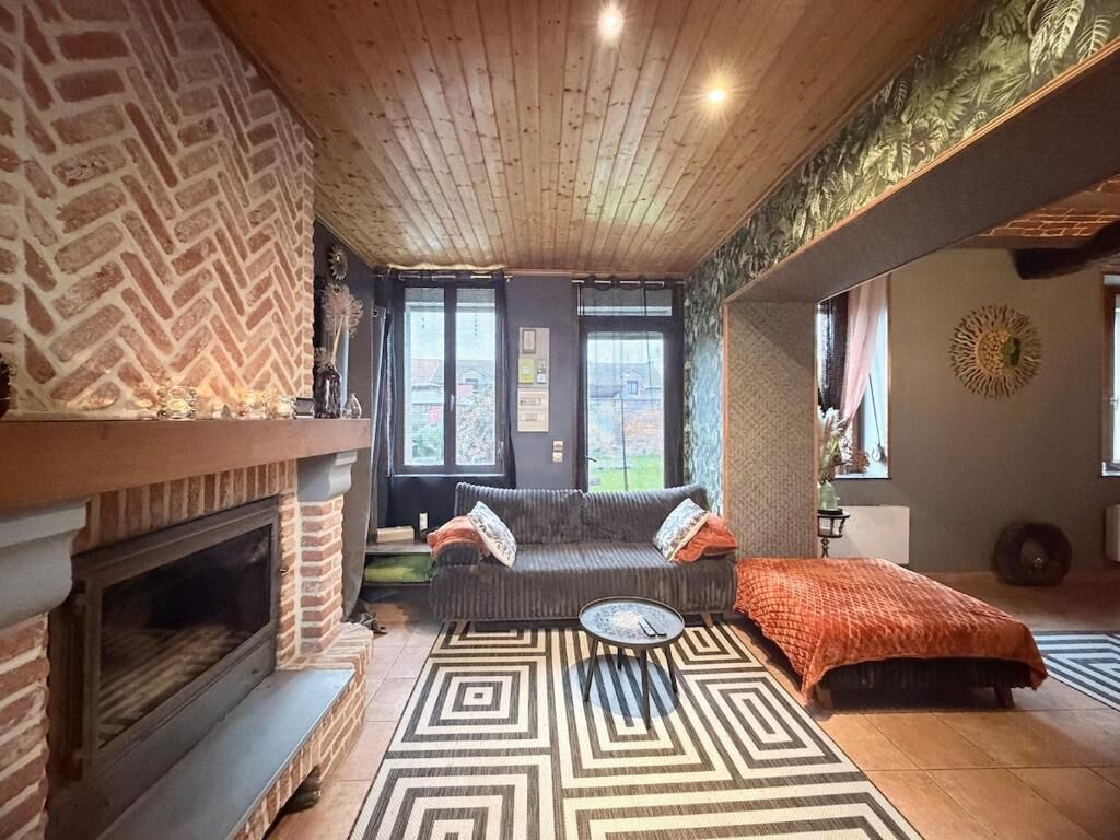 Una sala de estar acogedora con chimenea, un sofá, una mesa de centro y un tapete estampado.