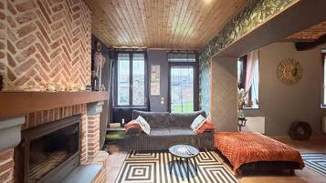 Una sala de estar acogedora con chimenea, un sofá, una mesa de centro y un tapete estampado.