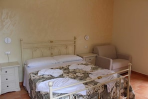 Un dormitorio con cama, una silla, una mesita de noche y un aparador.