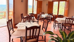 A dining area with tables and chairs, large windows, and a view of the outdoors. - Agriturismo il Carrubo (Ascea)