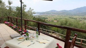 A table set outdoors with a scenic view of mountains and a valley. - Agriturismo il Carrubo (Ascea)