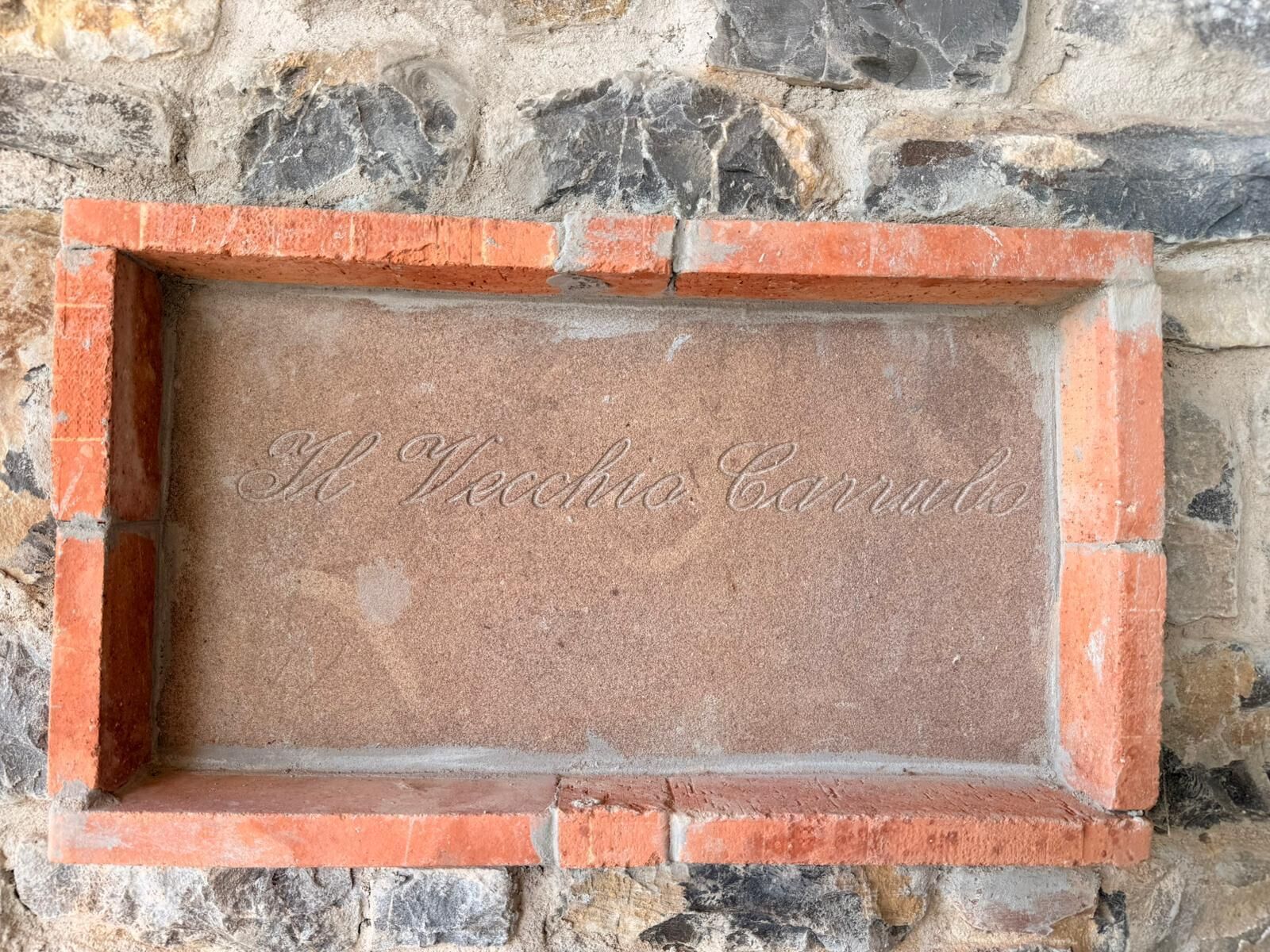 A stone wall with a brick frame containing an engraved name.