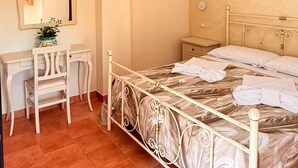 Un dormitorio con cama, escritorio, silla, espejo y lámpara en el techo.