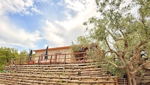 Un edificio de piedra con una escalera de madera y un árbol en primer plano.