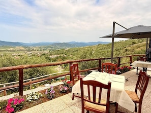 Una terraza con mesa y sillas, con vistas a un paisaje pintoresco con colinas y un pueblo.