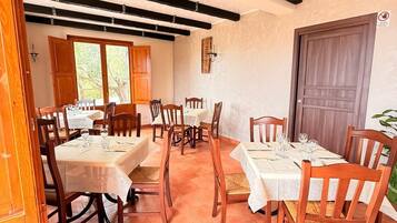 A dining area with wooden tables and chairs, a tiled floor, and a wooden door.