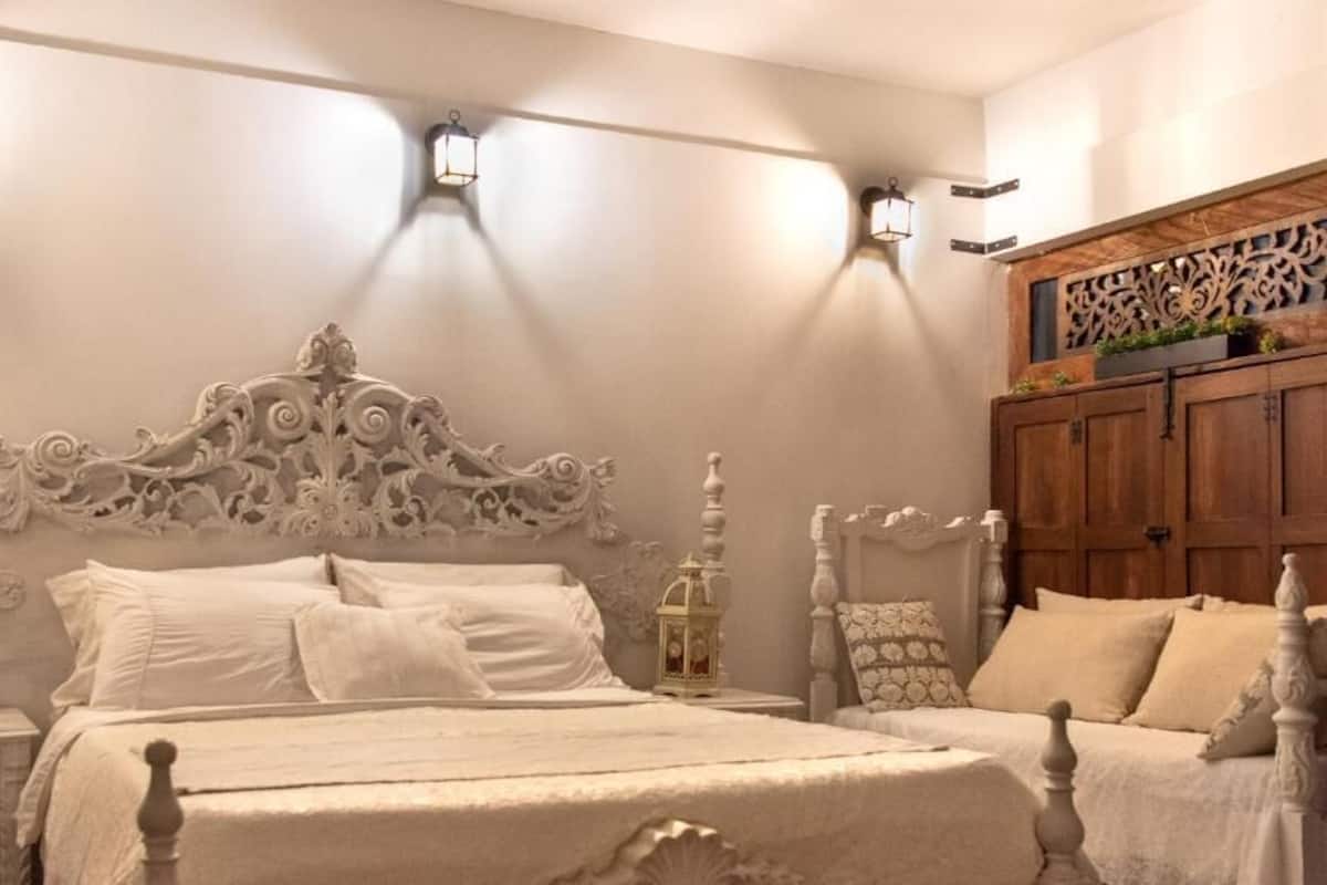 A bedroom with a white ornate bed, bedside lanterns, and a wooden cabinet.