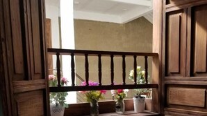 A room with a window, a table with a potted plant, a blue chair, and wooden paneling. - Casa ensueño hogar boutique  (Guaduas)