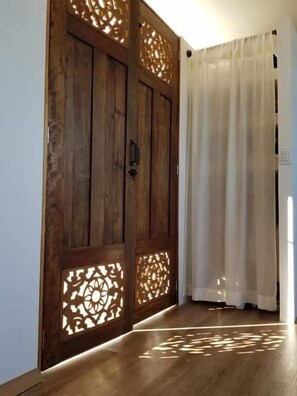 Un pasillo con puertas de madera y una cortina blanca.