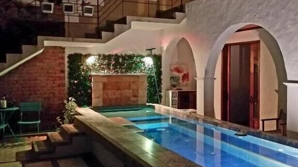 Una piscina con borde de piedra, una escalera y un balcón con barandillas.