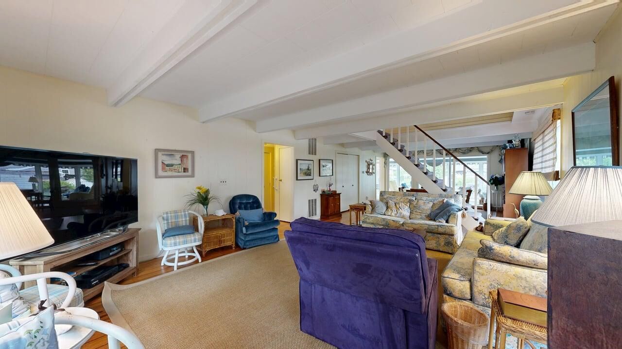 A spacious living room with a television, seating area, and a staircase leading to another level.